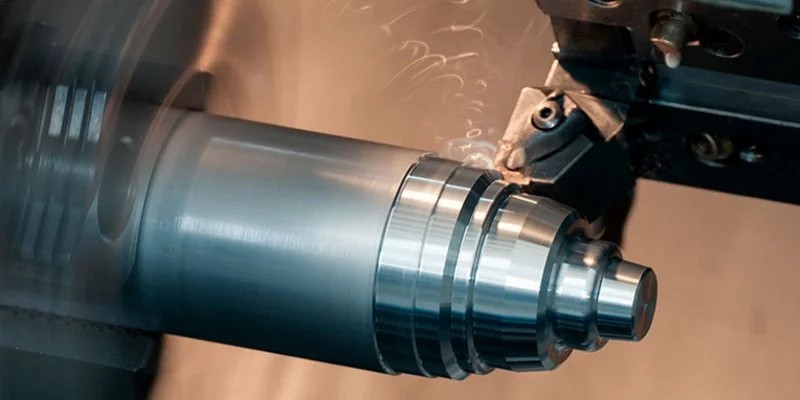 CNC lathe precision-turning a cast metal component with active coolant and swarf